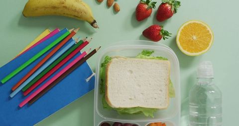 Healthy packed lunch with fresh fruits and school supplies