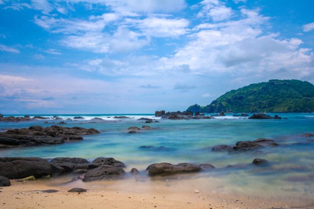 Serene Tropical Beach with Clear Blue Water and Rocky Shoreline - Download Free Stock Photos Pikwizard.com
