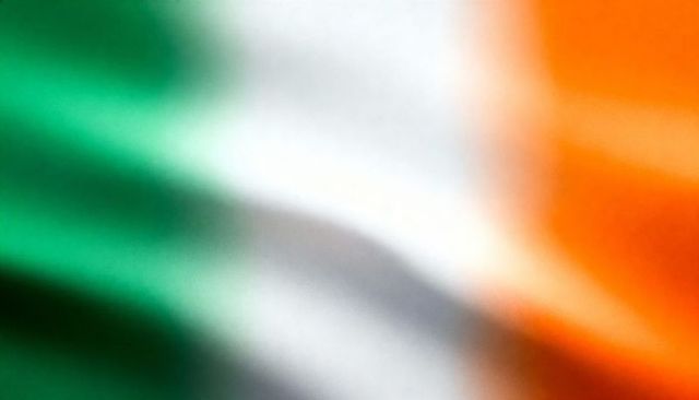 Soft-focus irish tricolor fabric close-up, blurred green white orange draped folds texture