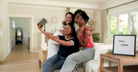 Happy Friends Capturing Memories During School Reunion Indoors