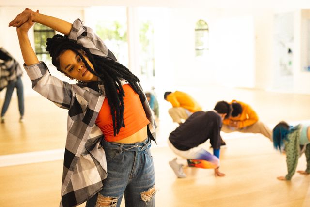 Diverse group of dancers stretching together in modern dance studio. Image shows dancers wearing casual attire, some performing different stretching exercises. Ideal for use in articles or promotions related to dance classes, fitness programs, community activities, teamwork, and urban lifestyle.