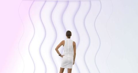 Woman in white dress contemplating abstract wavy art