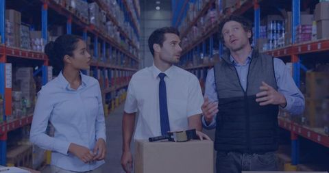 Warehouse team discussing logistics around carton and barcode scanner in racking aisle