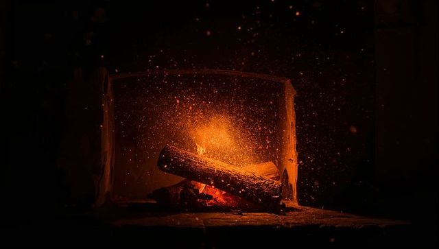 Crackling logs sending sparks in cozy fireplace glow