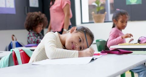 Young Student Smiling While Writing at Classroom Desk - Download Free Stock Images Pikwizard.com