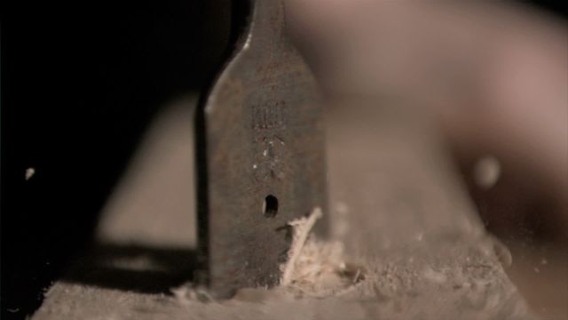 This stock photo captures a detailed close-up of a drill bit working on a piece of wood in super slow motion. Ideal for illustrating concepts of woodworking, carpentry, craftsmanship, DIY projects, and construction processes, it highlights the precision and detail involved in drilling and working with wood. Suitable for use in educational materials, industrial guides, workshops, blogs about woodworking, and construction-themed publications.