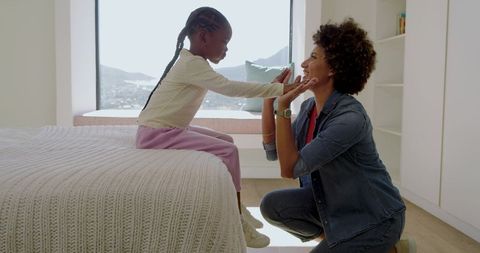 Mother and Daughter Nurturing Bond in Cozy Bedroom Setting