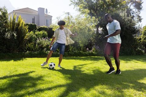 Diverse Friends Playing Soccer in Green Backyard