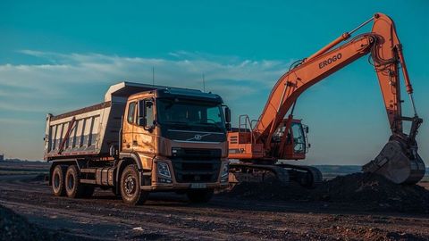 Excavator and dumper truck on construction site during sunset