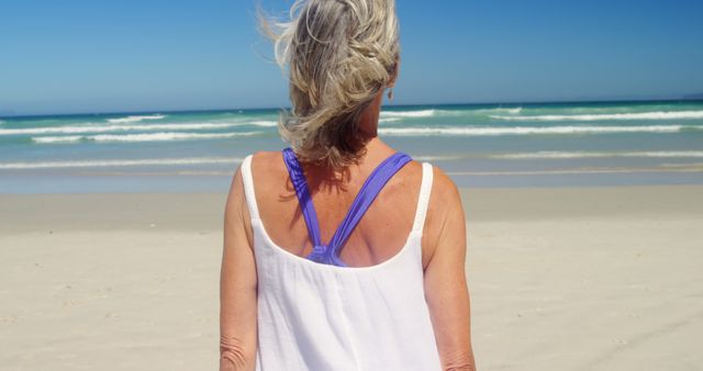 Senior Woman Enjoying Solitude on Sandy Beach with Ocean Waves - Download Free Stock Images Pikwizard.com