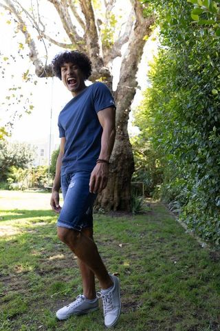 Joyful young man laughing in sunlit backyard