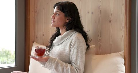 Woman Relaxing with Tea in Cozy Wooden Alcove Near Window