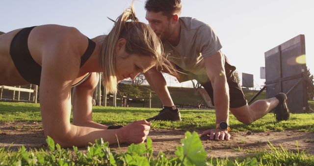 Fit couple doing plank exercises outside on a sunny day. Perfect for fitness and wellness articles, advertising gym sessions, promoting outdoor sports activities, and exercise blogs.