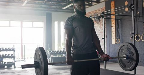 Focused African American Lifter Training with Barbell in Gym