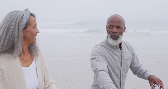 Senior Couple Walking on Beach on Overcast Day - Download Free Stock Images Pikwizard.com