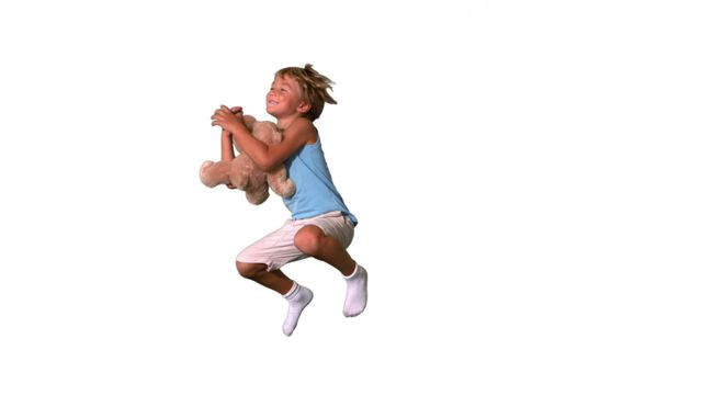 Boy happily jumping and cuddling teddy bear, expressing joy and playfulness. Video can be used in advertising, campaigns promoting children's products, websites focusing on child development, or articles on parenting and happiness.