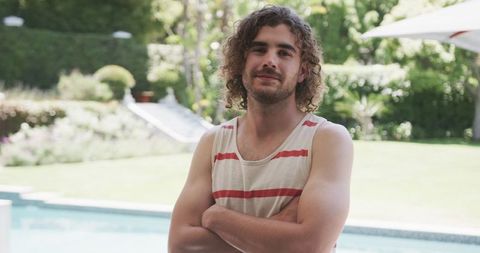 Relaxed Young Man with Curly Hair Standing Poolside