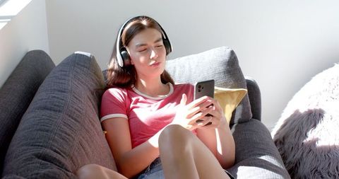 Teenage Girl Relaxing with Headphones and Smartphone at Home