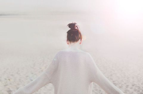 Woman Wearing Light Sweater Embracing Calm Beach Sunrise, Minimalist Coastal Lifestyle