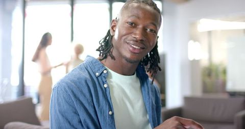 Smiling Man Using Smartphone in Modern Office Lounge