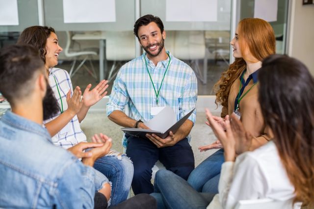 Group of executives showing appreciation for their colleague during a presentation in a modern office. Ideal for use in business articles, teamwork and collaboration promotions, success stories, and professional development materials.