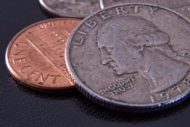 Close-up view of US currency, focusing on a quarter and a penny. Useful for stock photos, financial articles, economical presentations, and educational material on American currency.