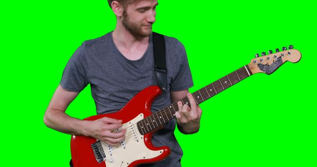Male musician playing guitar against green screen