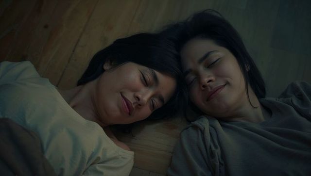 Two women lying together on wood floor sharing quiet intimate moment at home in casual tees