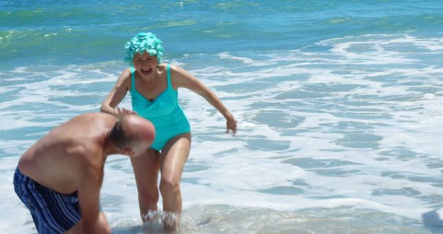 Senior friends playing in water at the beach