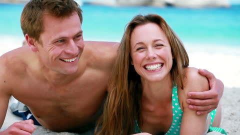 Happy Couple Relaxing on Sandy Beach in Summer Sun