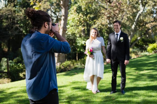 Photographer taking photo of newly married couple in park