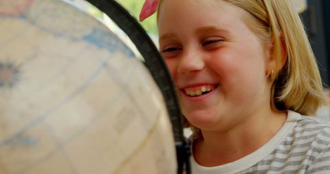 Joyful Schoolgirl Exploring Geography with Globe in Classroom