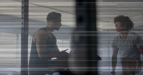 Three men discussing training plan in gym showing teamwork, coaching and focus