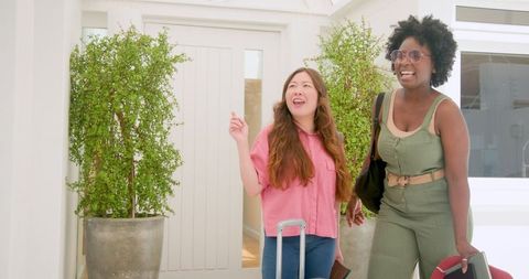 Happy friends arriving at vacation hotel with luggage