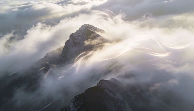 Glowing Light Trails Weaving Through Misty High Alpine Ridge and Jagged Summit at Sunrise