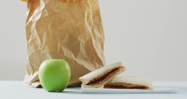 Peanut butter and jelly sandwich with apple and paper bag against white background. food and nutrition concept
