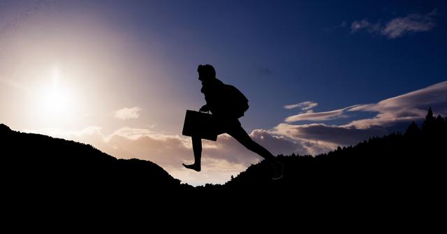 Digital composite of Silhouette businessman leaping on mountain during sunset