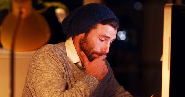Thoughtful Man in Beanie Staring at Computer Screen - Download Free Stock Photos Pikwizard.com