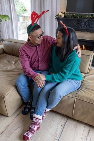 Couple embracing holiday spirit with antlers by fireplace