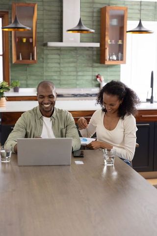 African American couple working on laptop at modern kitchen table planning finances