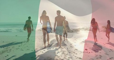 Surfers Walking Toward Ocean in Sunset Light on Sandy Beach