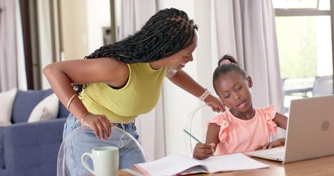 African american mother helping daughter with homework on laptop for remote learning