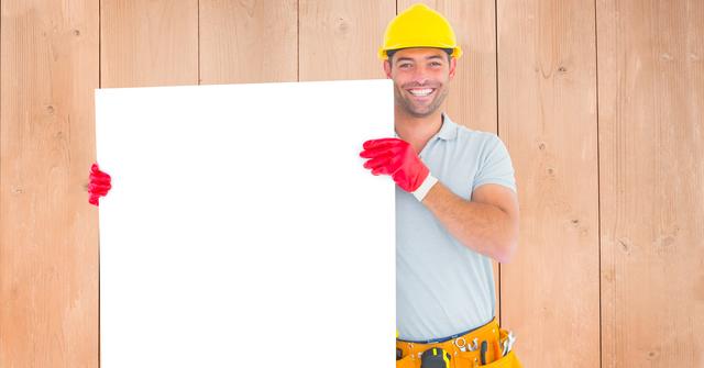 Repairman holding a blank billboard with wooden wall background. Useful for advertising, promotional materials, marketing content, handyman service commercials, and construction industry posters.