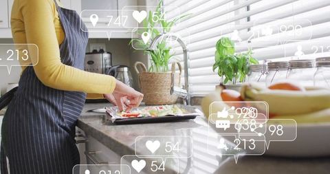 Woman in apron preparing vegetable tray in bright kitchen with social media icons
