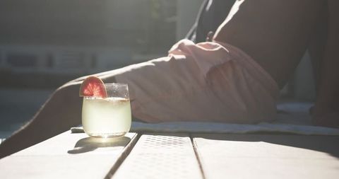 Relaxing poolside at golden hour with grapefruit cocktail and sunlit swimwear