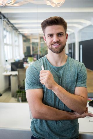 Confident man holding stylus in modern office environment