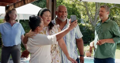 Senior Friends Smiling and Taking Selfie in Sunny Garden