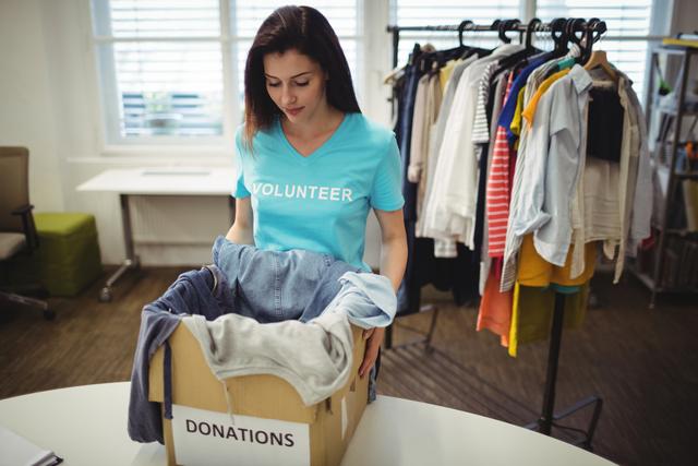 Female volunteer holding clothes in donation box at workshop