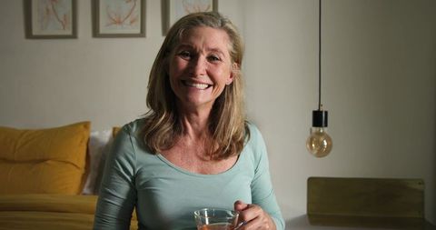 Smiling senior woman relaxing with warm drink in cozy bedroom