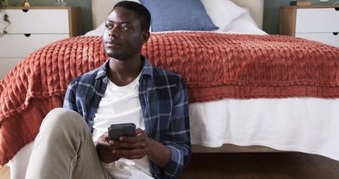 Man relaxing with smartphone in modern bedroom interior